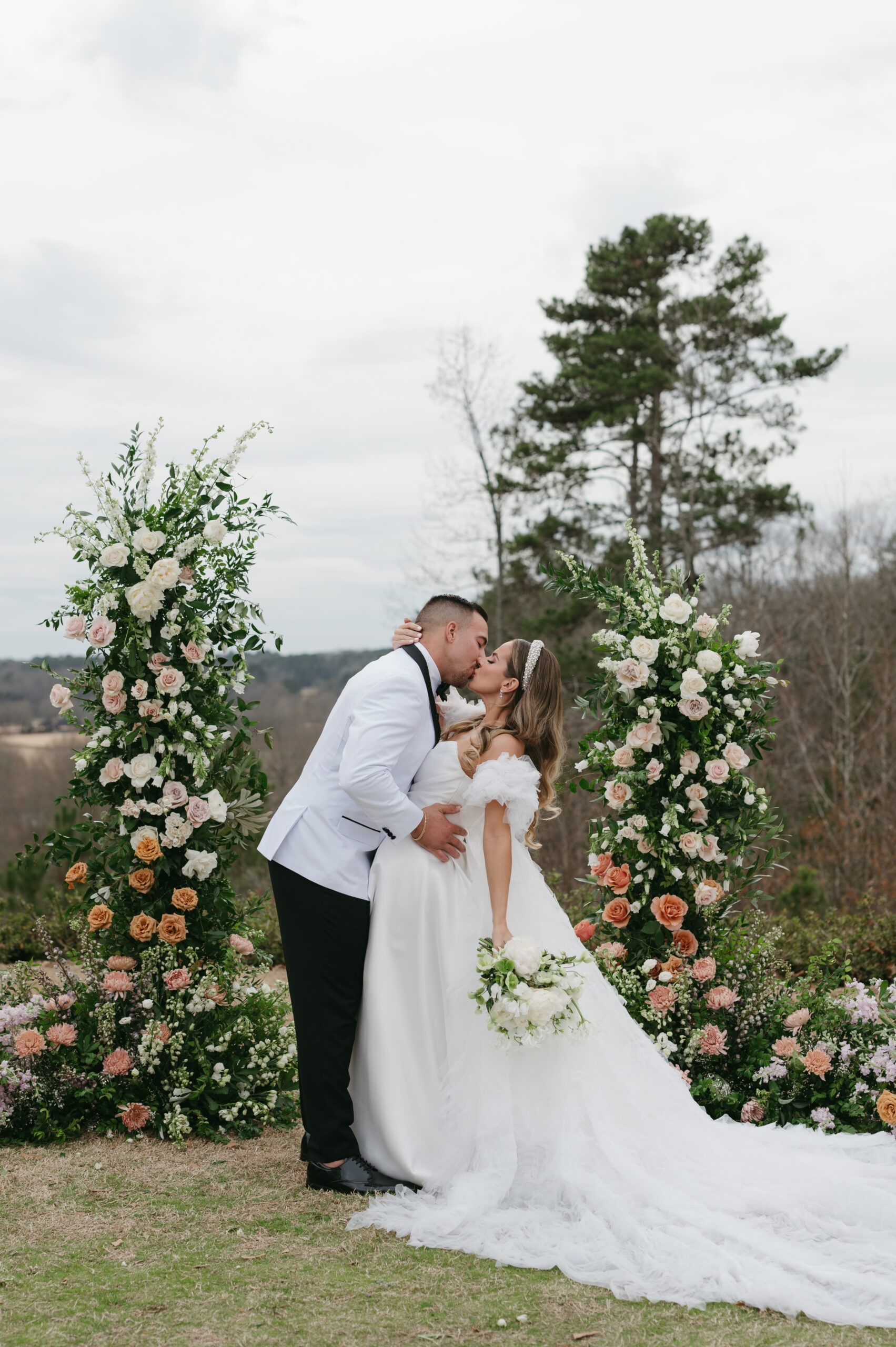 Modern wedding portraits with a bride with a bridal headband and groom with a white suit in front of their colorful floral arch. | Megan Kuhn Photography
