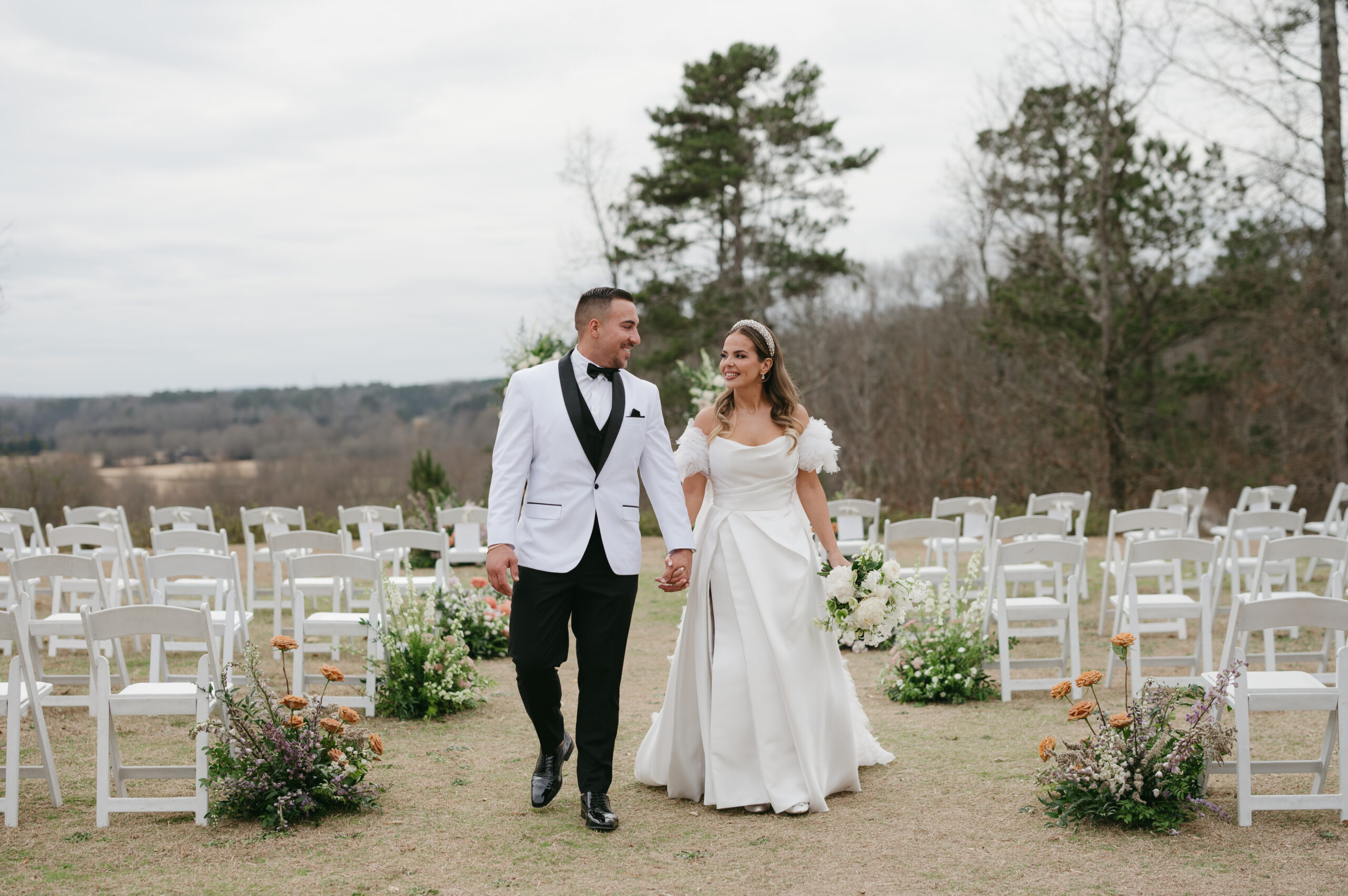 Modern wedding portraits with a bride with a bridal headband and groom with a white suit in front of their colorful floral arch. | Megan Kuhn Photography