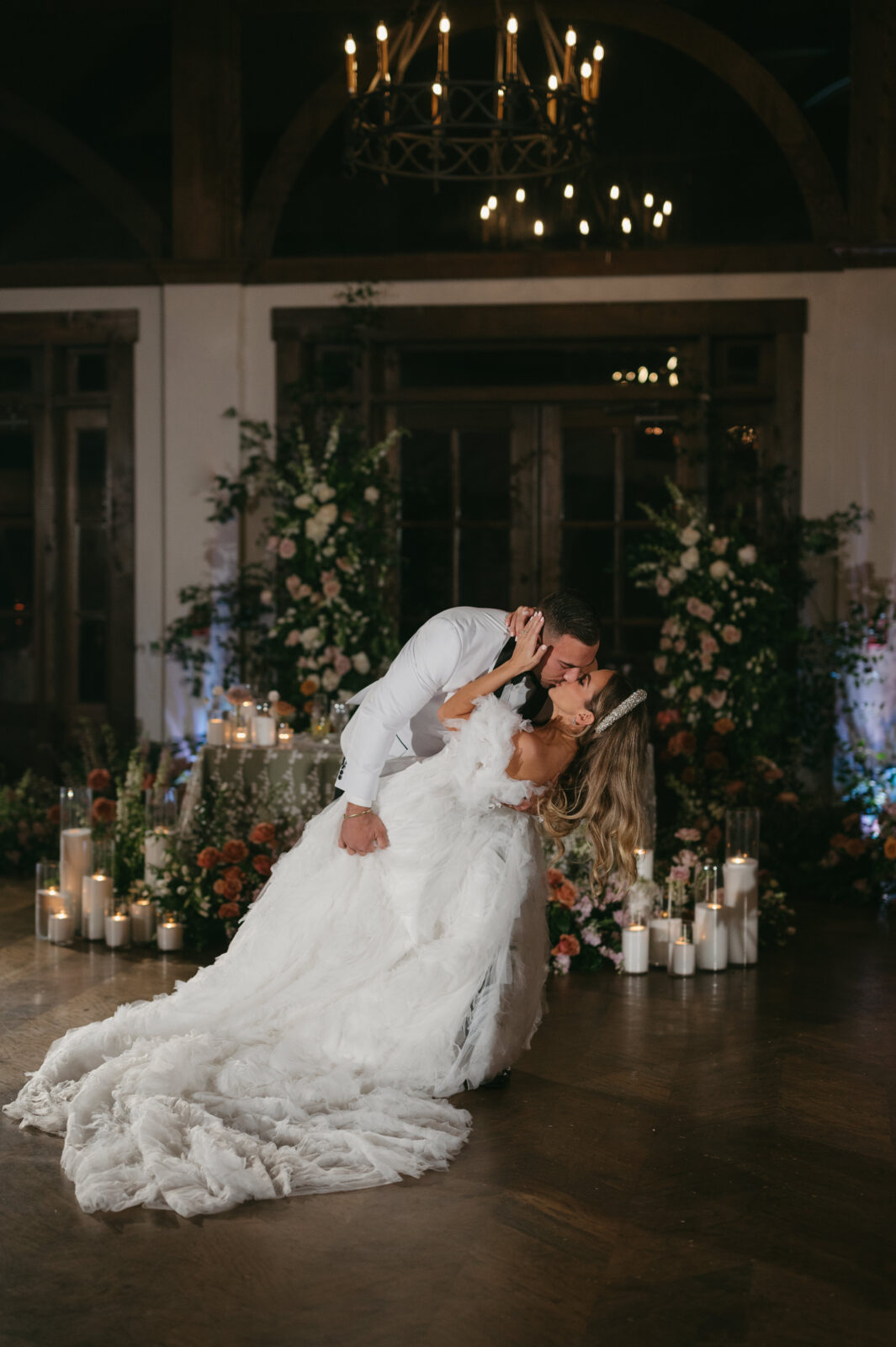 Indoor wedding first dance at Foxhall Resort with a textured bridal cape and a floral head table | Megan Kuhn Photography