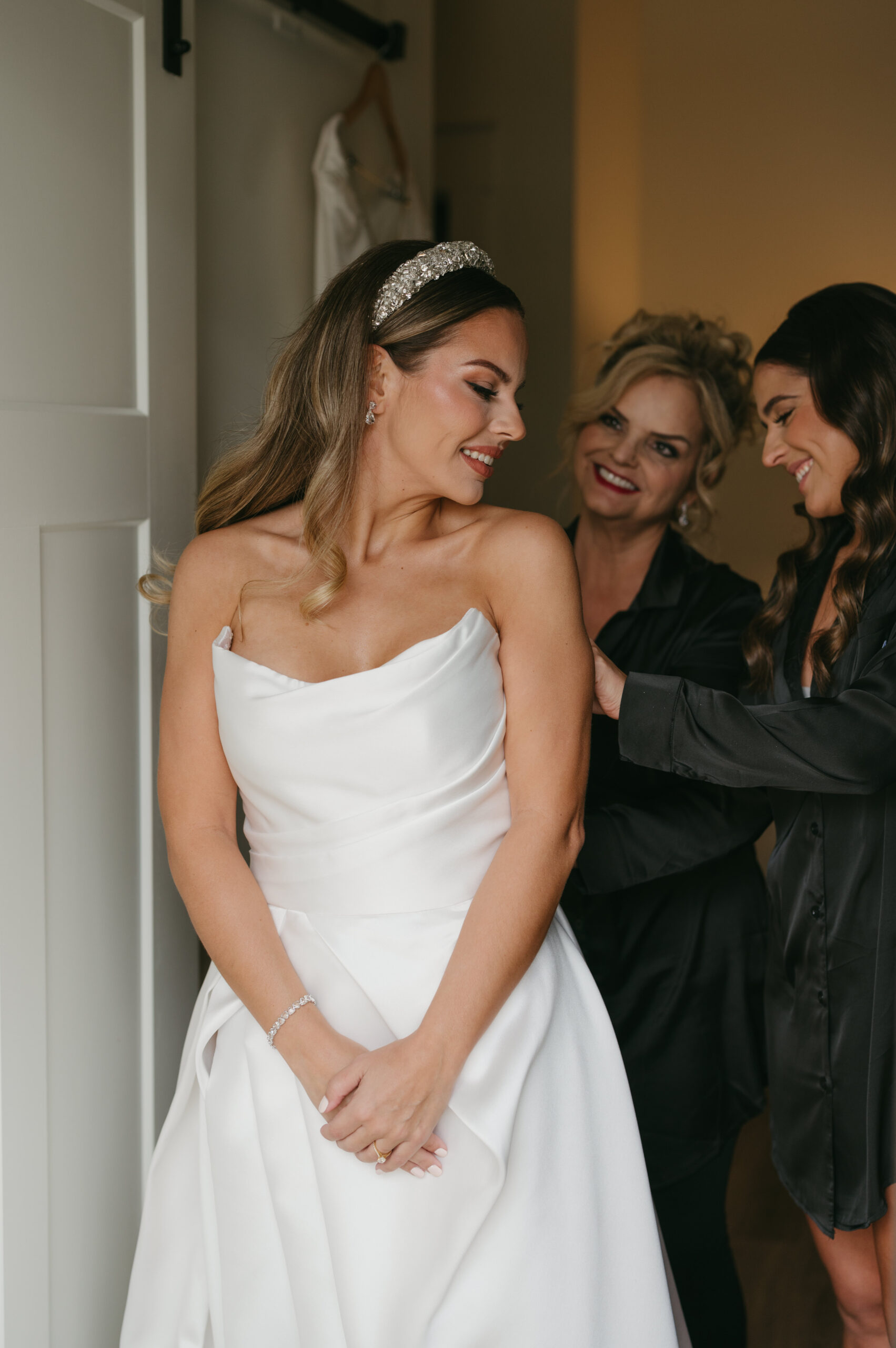 This colorful luxury wedding full of florals and candlelight at Foxhall Resort was made of dreams. Chantelle had her mom and sister zip her wedding dress during getting ready photos. | Megan Kuhn Photography